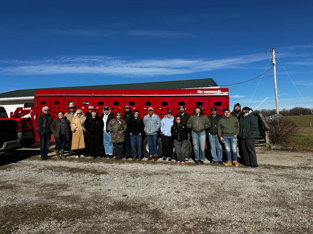 Red Hog staff and guests visiting Our Home Place Meat’s Berry Beef partners in Henry County, Kentucky, gathered in front of a red farm trailer.